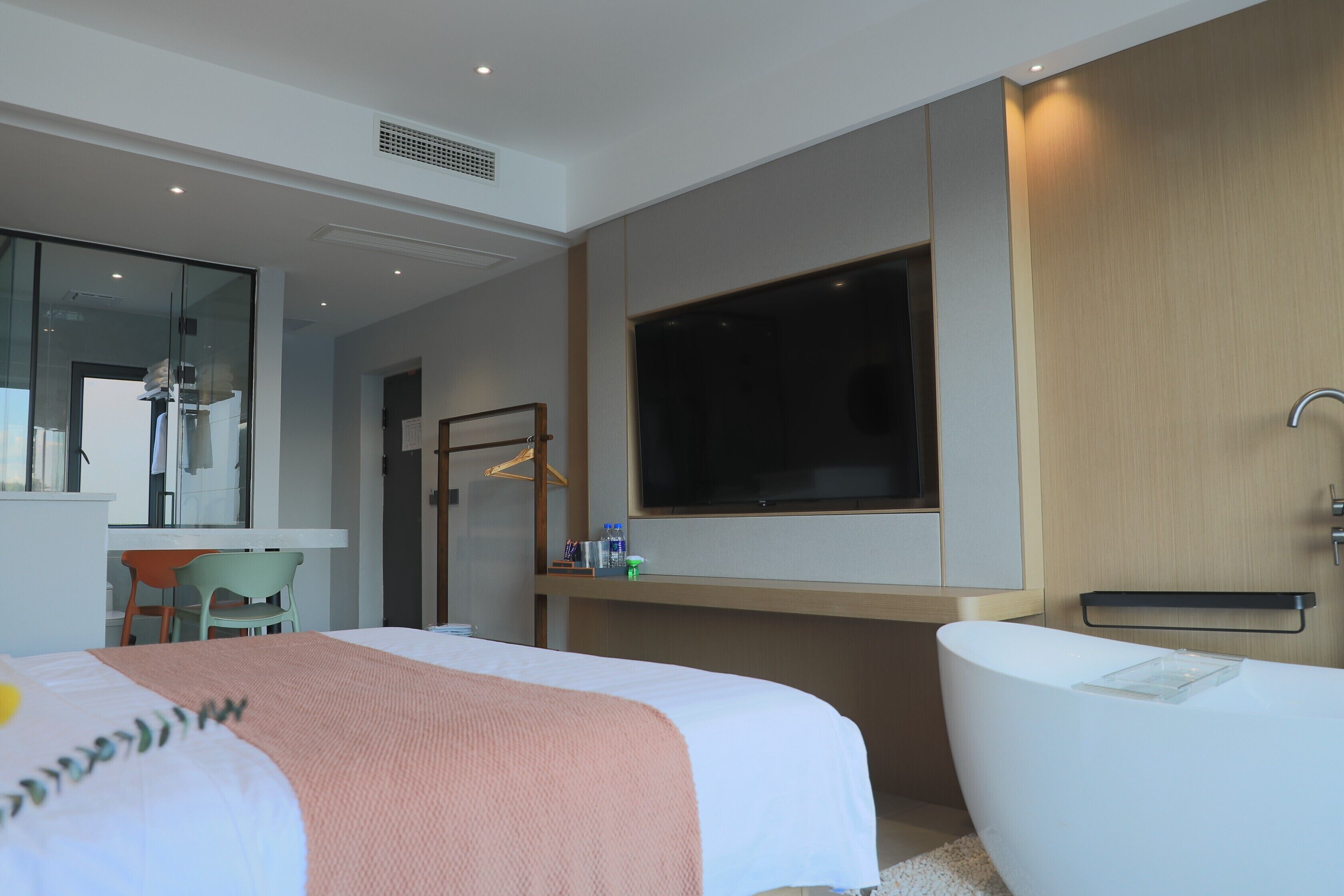 Una habitación de hotel moderna con una cama grande, una bañera, un escritorio y un televisor.