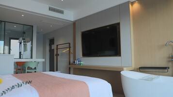 Una habitación de hotel moderna con una cama grande, una bañera, un escritorio y un televisor.