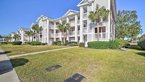 A row of multi-story buildings with balconies, a well-maintained lawn, and a clear blue sky. - Tee Times, Poolside Vibes! Myrtle Beach Retreat (Myrtle Beach)