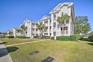 A row of multi-story buildings with balconies, a well-maintained lawn, and a clear blue sky. - Tee Times, Poolside Vibes! Myrtle Beach Retreat (Myrtle Beach)