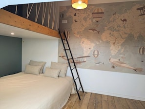A bedroom with a loft bed, a world map mural, and a ladder.