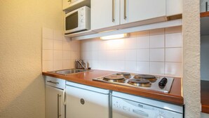 Uma cozinha compacta com micro-ondas, fogão, pia e armários brancos.