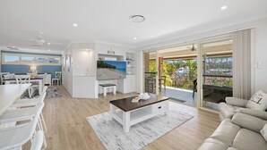Una sala de estar moderna con comedor, televisor de pantalla plana y balcón con vistas.