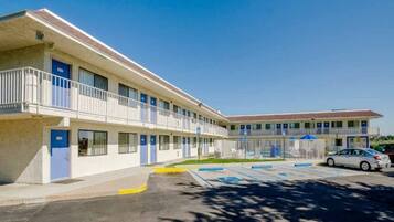 A motel with a two-story structure, a parking lot, and a clear blue sky.