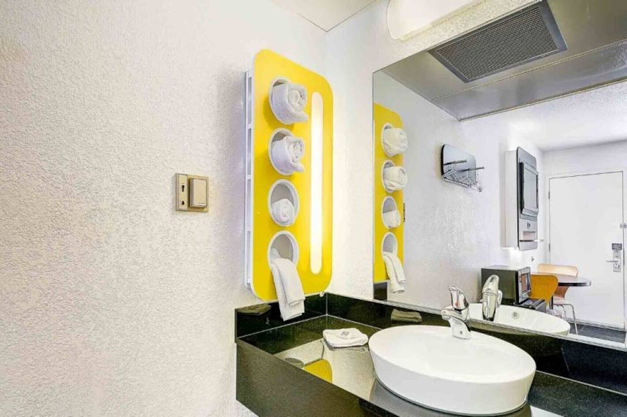 Un baño moderno con un toallero amarillo, un lavabo blanco y un espejo.