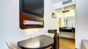 A compact room with a round table, a television mounted on the wall, a microwave, and a small seating area. - 2 Full Beds | Non-Smoking (Thornton)