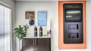 Un baño moderno con un lavamanos, una planta en maceta y un cargador mural.