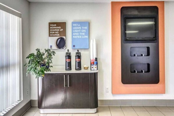 A modern bathroom with a sink, a potted plant, and a wall-mounted charging station.