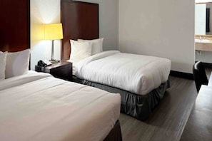 A hotel room with two beds, a nightstand with a lamp, a desk, and a chair. - 2 Queen Beds | Smoking, Micfridge (Mesa)