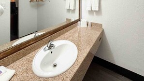 Une salle de bain avec un lavabo blanc, un miroir et un porte-serviettes.