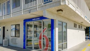 A building entrance with a blue 'welcome' sign, large glass windows, and a visible number '6' on the facade. - Queen Bed|Nsmk|Thornton (Thornton)