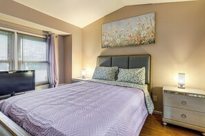 Quarto com cama, televisão, mesa de cabeceira e um quadro na parede.