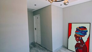 Ein Flur mit einem modernen Kronleuchter, einer Tür und einem farbenfrohen Gemälde an der Wand.