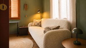 Een gezellige kamer met een bank, een lamp, een klein tafeltje en een raam met jaloezieën.
