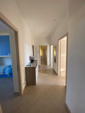 Ein Flur mit einer Rezeption, einem Bett im Hintergrund und einer Tür zu einem weiteren Zimmer.