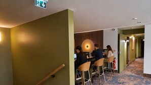 Un hall d’hôtel avec un escalier, un espace salon avec des tables et un extincteur.
