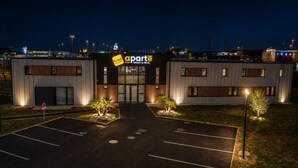 Un hôtel moderne, reconnaissable à son panneau « Aparthôtel » bien visible, doté d’un parking et d’une entrée bien éclairée.