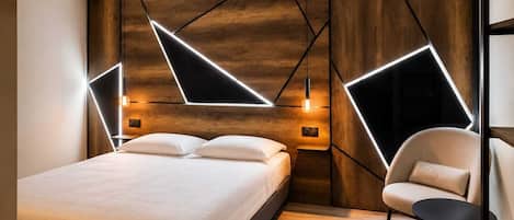 A modern bedroom with a bed, bedside tables, a chair, and geometric wall lighting.