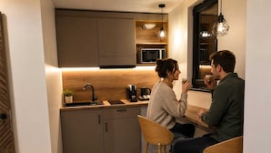 Une cuisine moderne équipée d’un four à micro-ondes encastré, d’une machine à café et d’un plan de travail en bois.