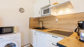 A compact kitchen with a washing machine, microwave, sink, and coffee maker. - Gite Le Micocoulier La Fontinelle – Peaceful Retreat in Ardèche Near Vallon Pont d'Arc (Bessas)