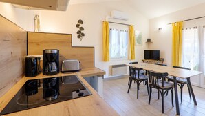 A modern kitchen with a coffee maker, toaster, and a dining area with chairs and a table. - Gite Le Micocoulier La Fontinelle – Peaceful Retreat in Ardèche Near Vallon Pont d'Arc (Bessas)