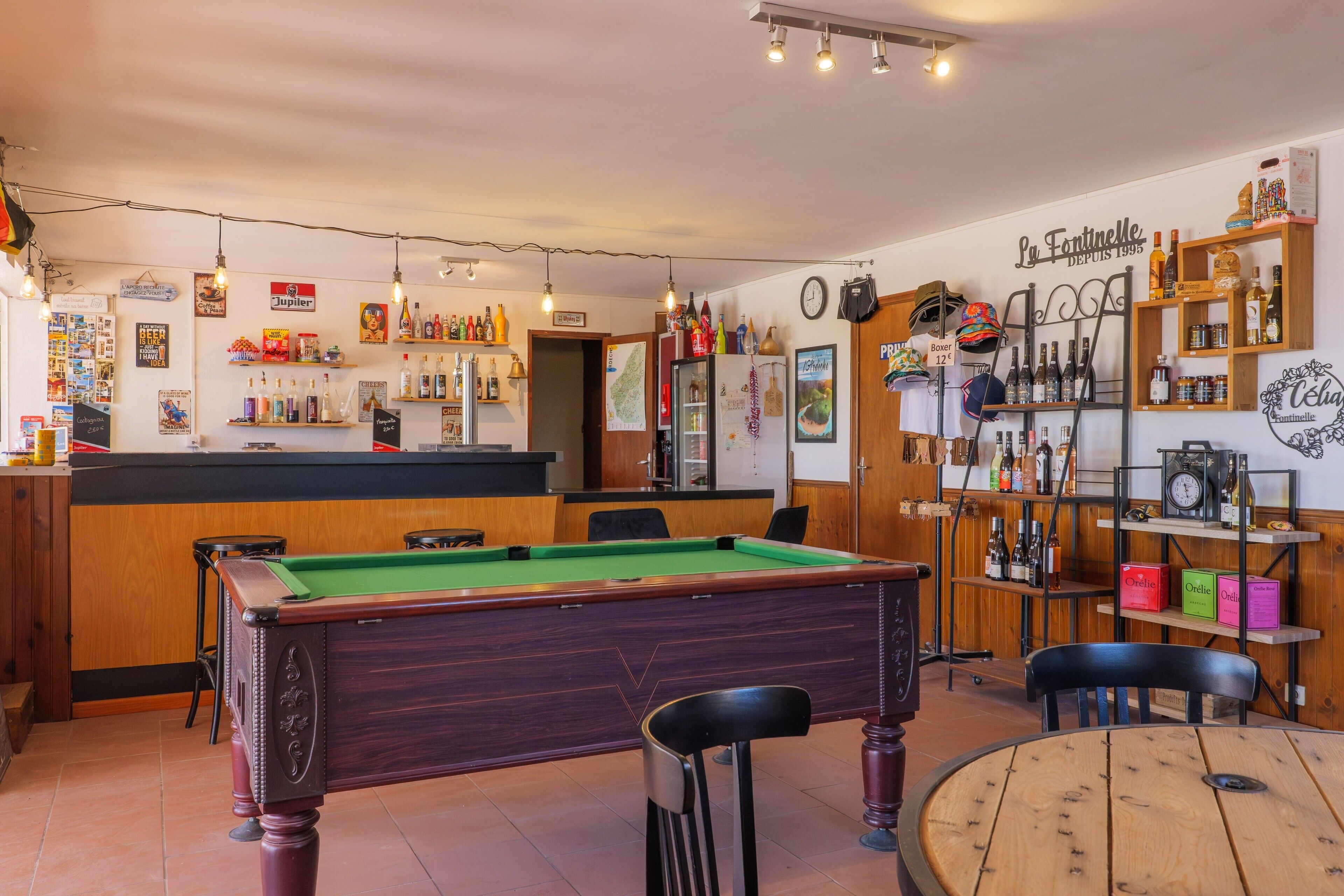 Un espace bar avec un billard, des chaises et des étagères remplies de bouteilles.
