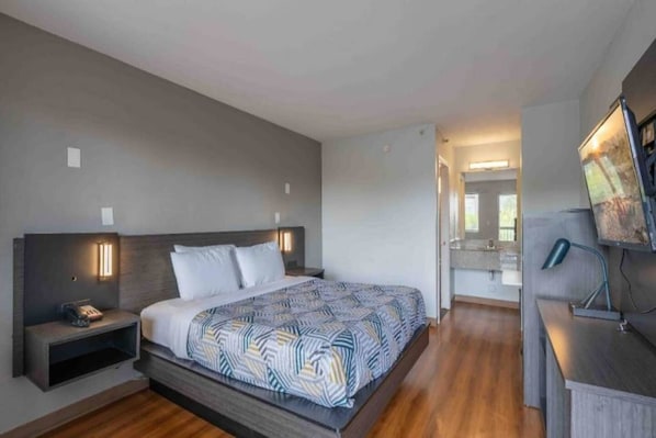 Une chambre d’hôtel moderne avec un grand lit, des tables de chevet, un bureau et un miroir.