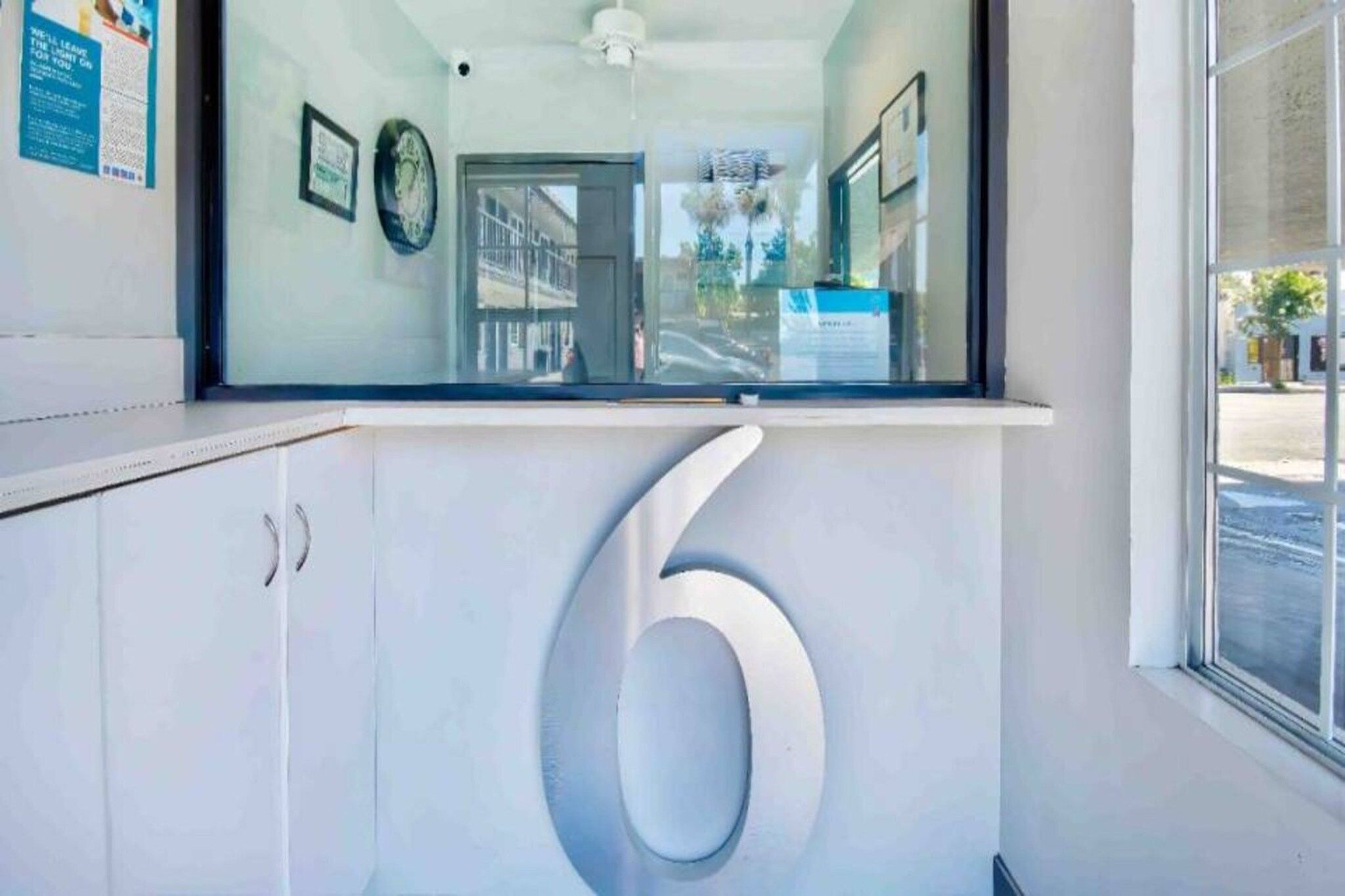 A hallway with a large number '6' on the wall, a door, and a window with a view of the street.