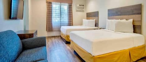 Habitación de hotel con dos camas, un sofá, un televisor y una ventana con cortinas.