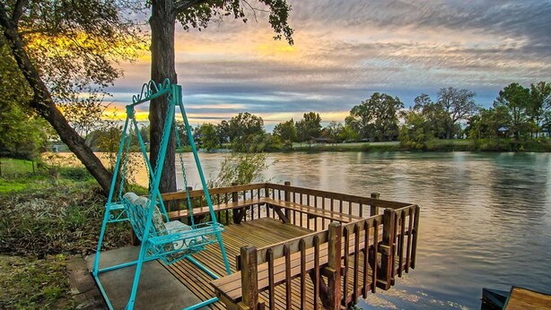 Une jetée en bois s’étendant au-dessus d’un lac paisible, une balançoire et un banc.