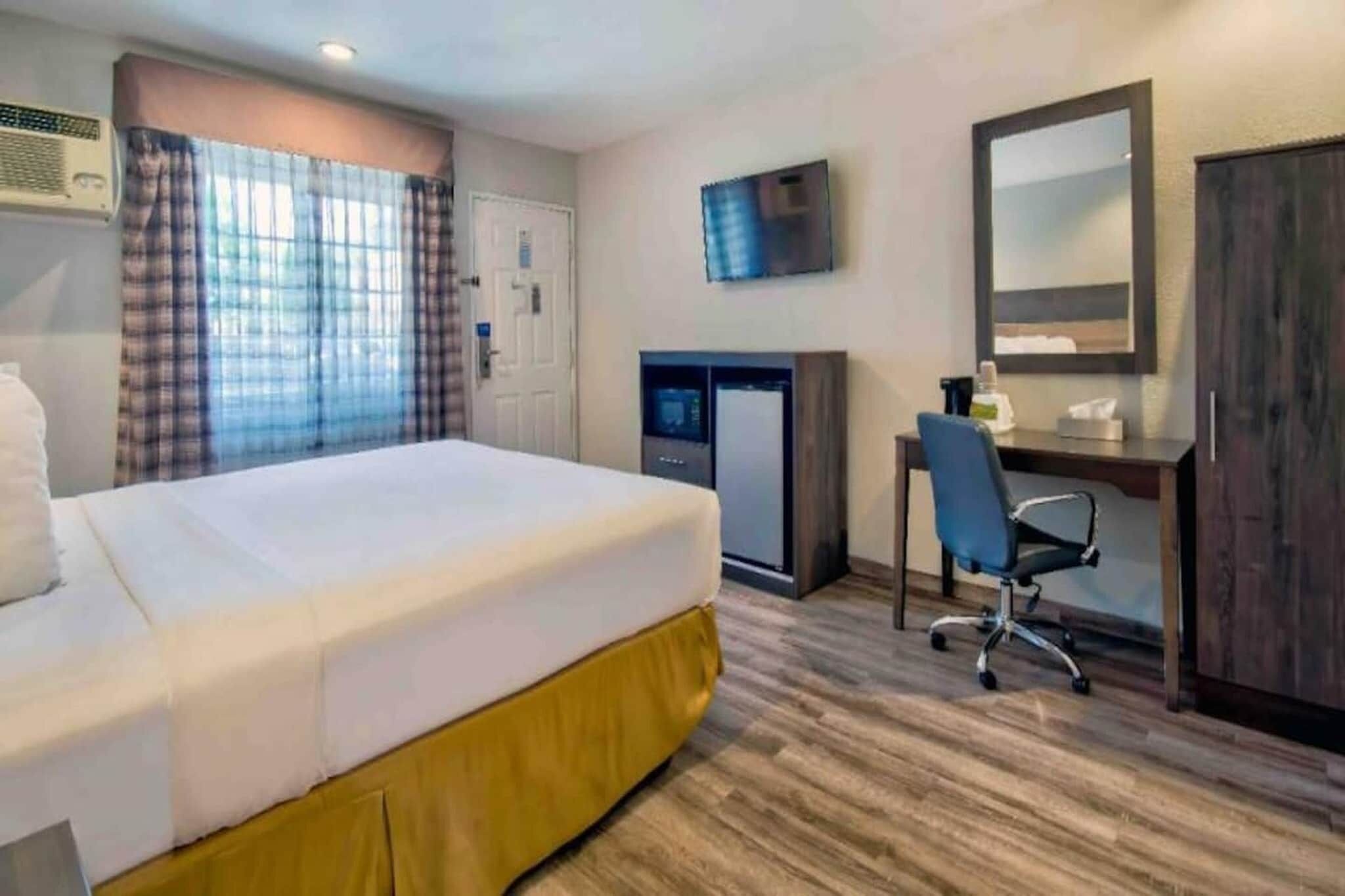 Een hotelkamer met een bed, een bureau, een stoel, een televisie en een kledingkast.