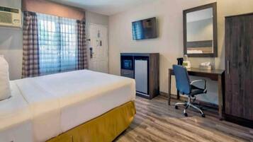 Een hotelkamer met een bed, een bureau, een stoel, een televisie en een kledingkast.