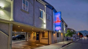 A hotel with a large illuminated sign, a covered entrance, and a parking area.