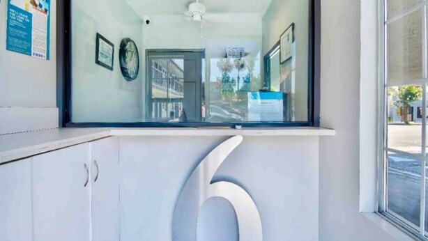 A reception area with a large number '6' on the wall, a glass door, and a window with a view of the street.