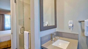 A bathroom with a glass shower enclosure, a sink, a mirror, and a towel rack.