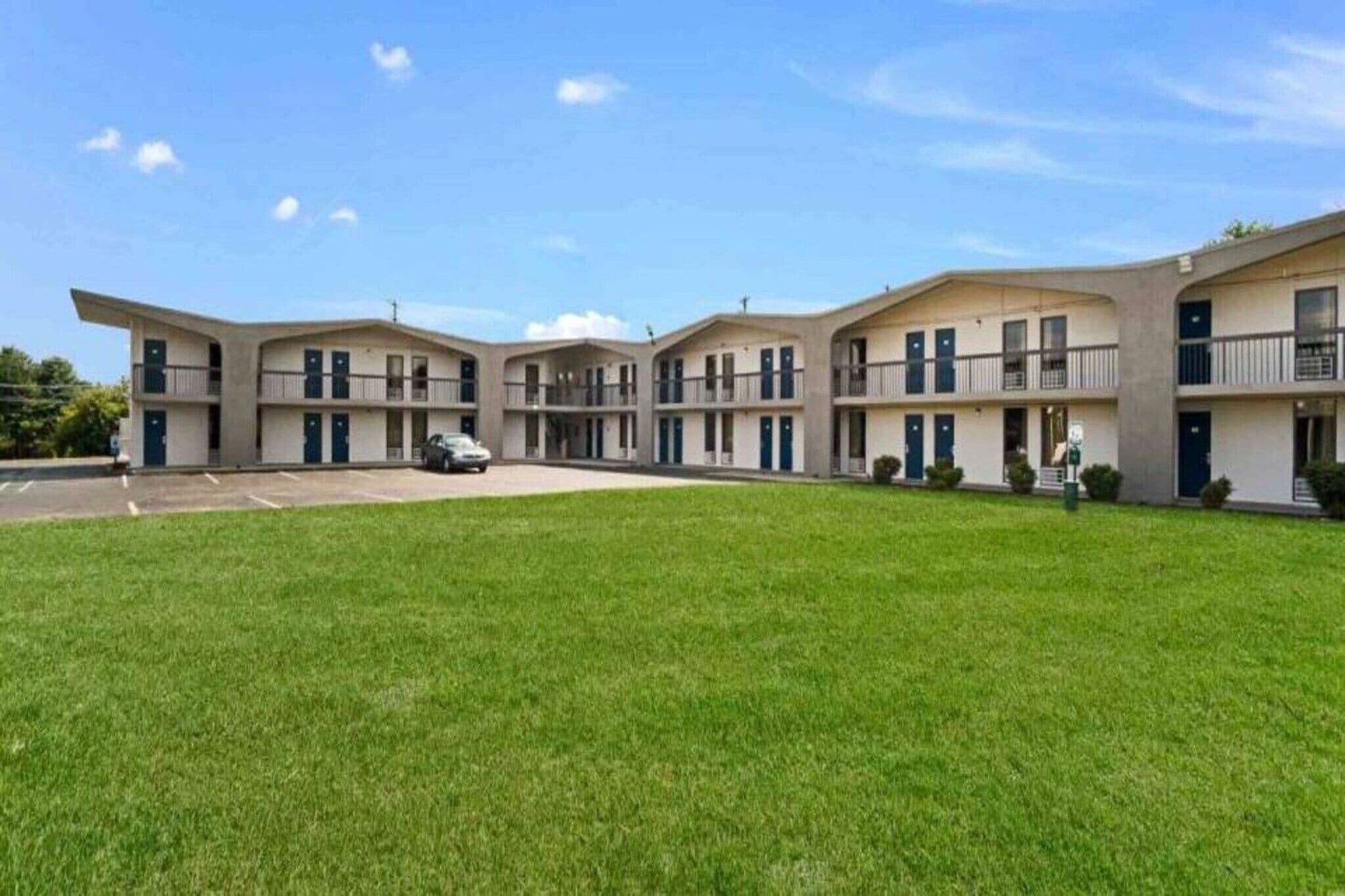 Un motel de varios pisos con un patio central, habitaciones individuales con balcones y un estacionamiento.