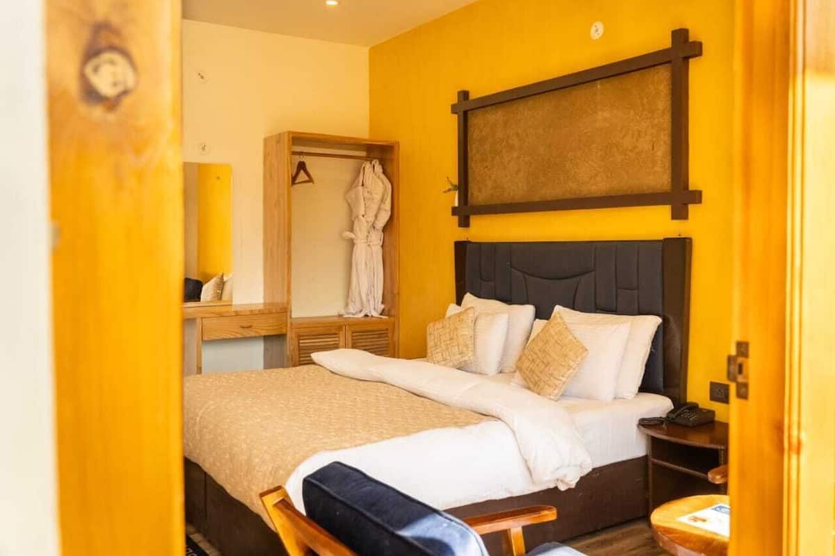 Una habitación de hotel con cama, mesita de noche, armario y espejo.