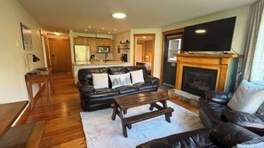 Ein Wohnzimmer mit einer schwarzen Ledersofa, einem Holztisch und einem Kamin.