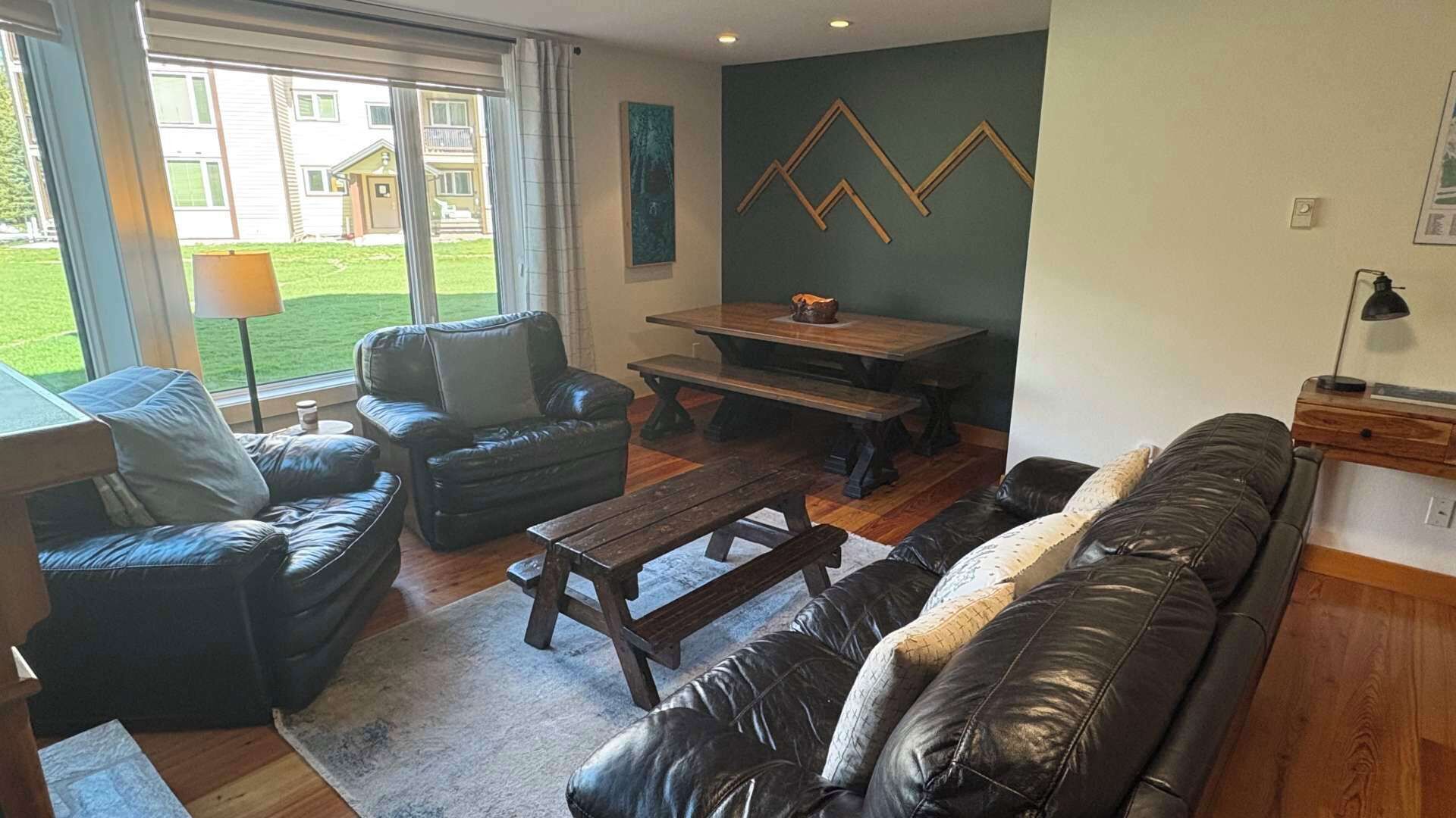 Un salon avec un canapé, une table basse et une table à manger. Il y a une fenêtre qui donne sur un bâtiment à l’extérieur.