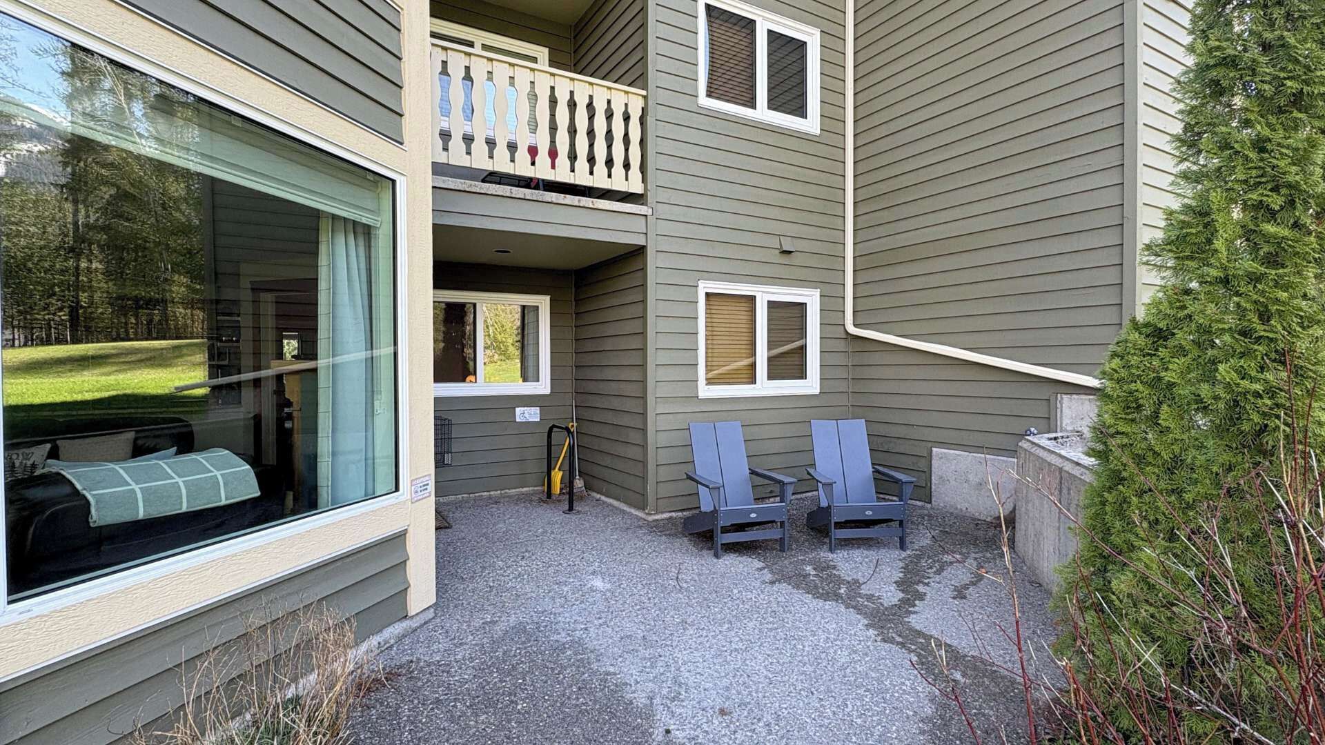 Un bâtiment à deux étages doté d’un balcon, d’une terrasse couverte avec deux chaises et d’une allée gravillonnée.