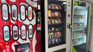 Ein Getränkeautomat mit verschiedenen Auswahlmöglichkeiten, ein Coca-Cola Automat und ein mit Snacks und Getränken gefüllter Kühlschrank.