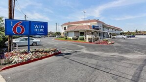 Ein Motel mit Schild zur Kennzeichnung von WLAN, einem Parkplatz und einem Gebäude mit rotem Dach.