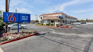 Ein Motel mit Schild zur Kennzeichnung von WLAN, einem Parkplatz und einem Gebäude mit rotem Dach.