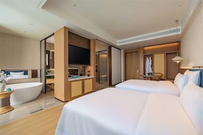 Ett modernt hotellrum med en stor säng, en separat sittgrupp, en platt-TV och ett badrum med dusch och toalett.