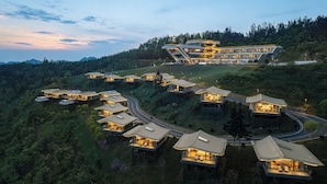A modern resort with multiple guest houses on a hillside, connected by winding roads.