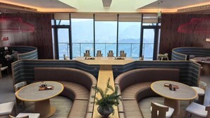 A modern hotel lobby with a central table, seating areas, and large windows offering a city view.