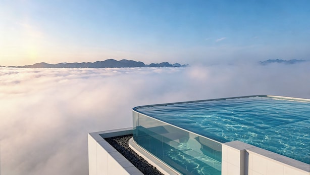 An infinity pool with a clear view of the clouds and mountains in the background.
