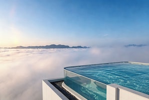 En infinitypool med fri sikt över molnen och bergen i bakgrunden.