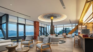 A modern interior with a large seating area, a central light fixture, and a view through large windows.