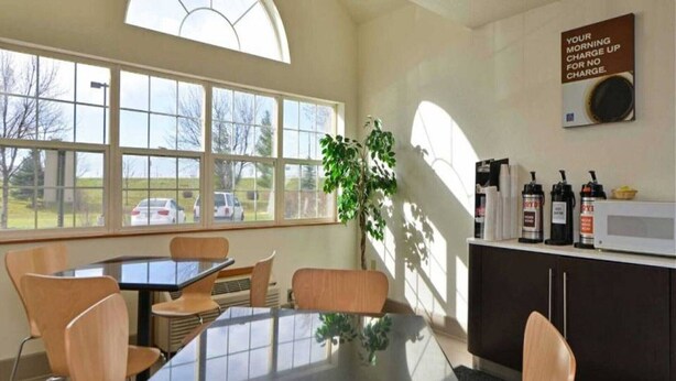 A room with a table, chairs, a potted plant, a microwave, and a coffee machine. - 1 Queen Bed | Suite, Non-Smoking (MERIDIAN)